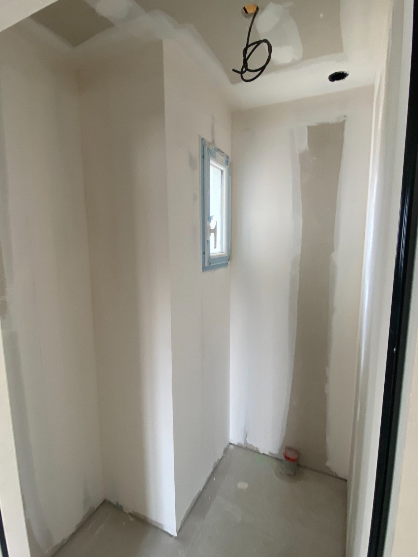 Salle de bains inachevée avec murs non peints et sol en béton.