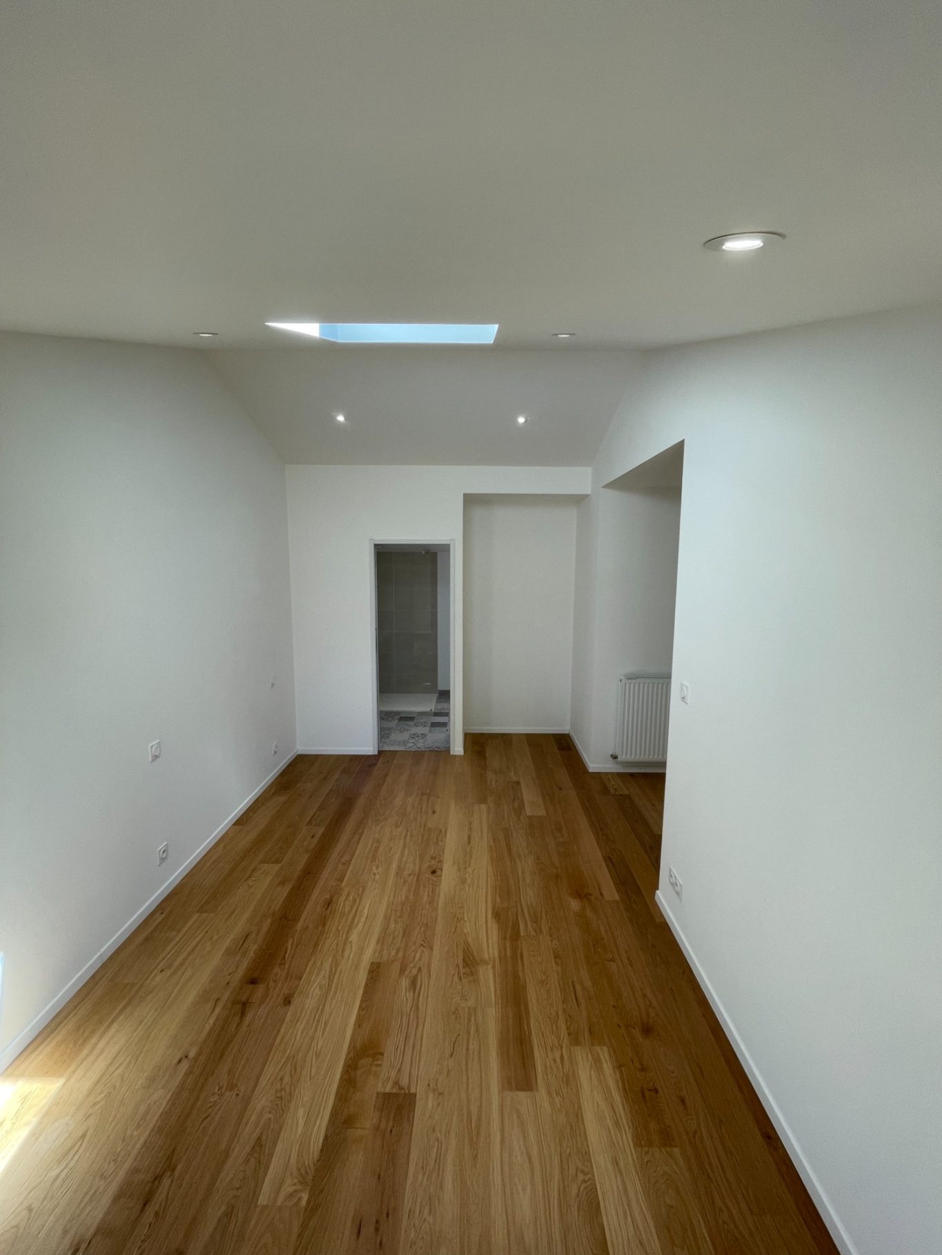 Intérieur d'une pièce spacieuse avec un sol en bois et des murs blancs.