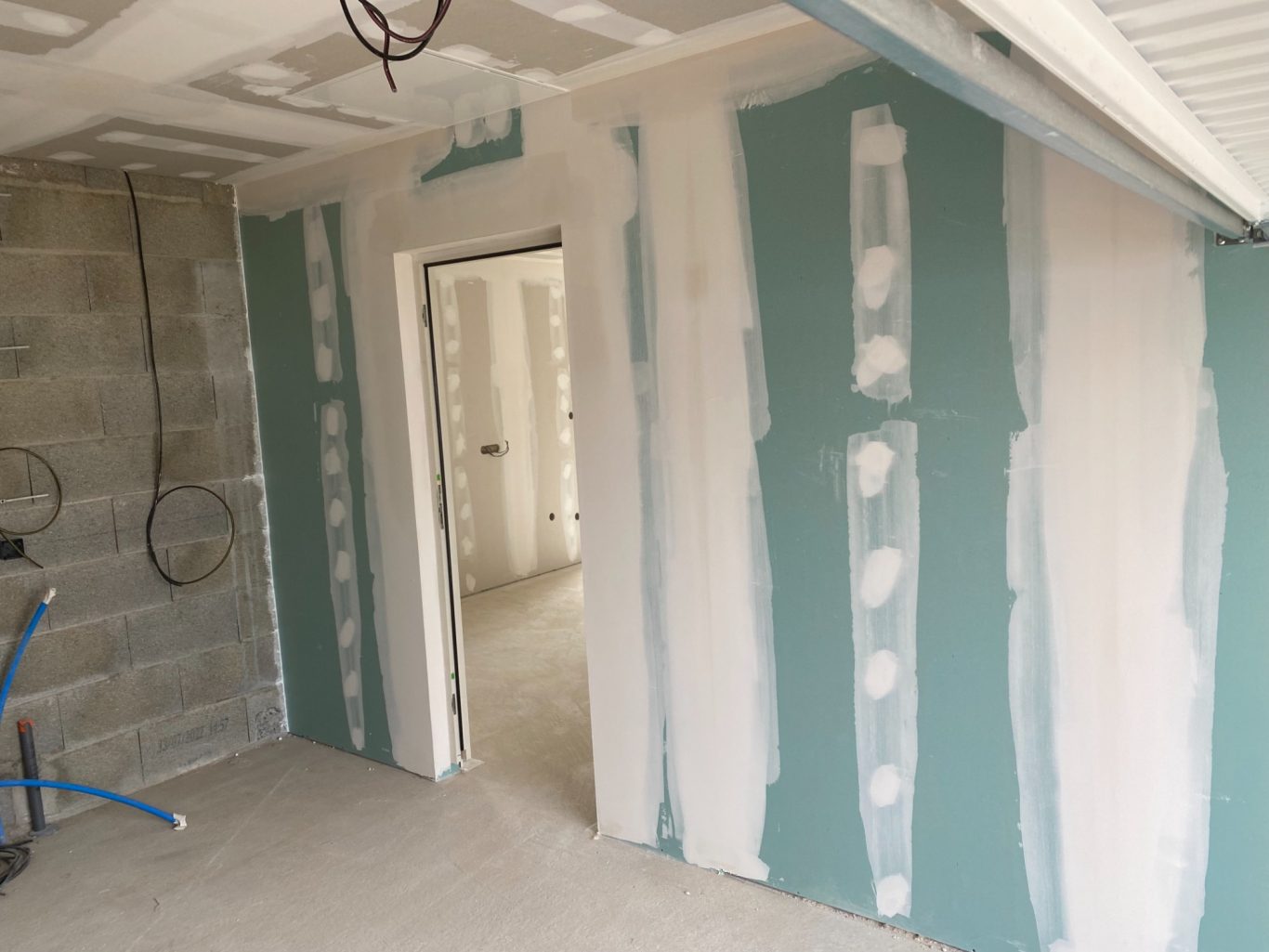 Mur en cours de finition avec des bandes de joint sur des plaques de plâtre.