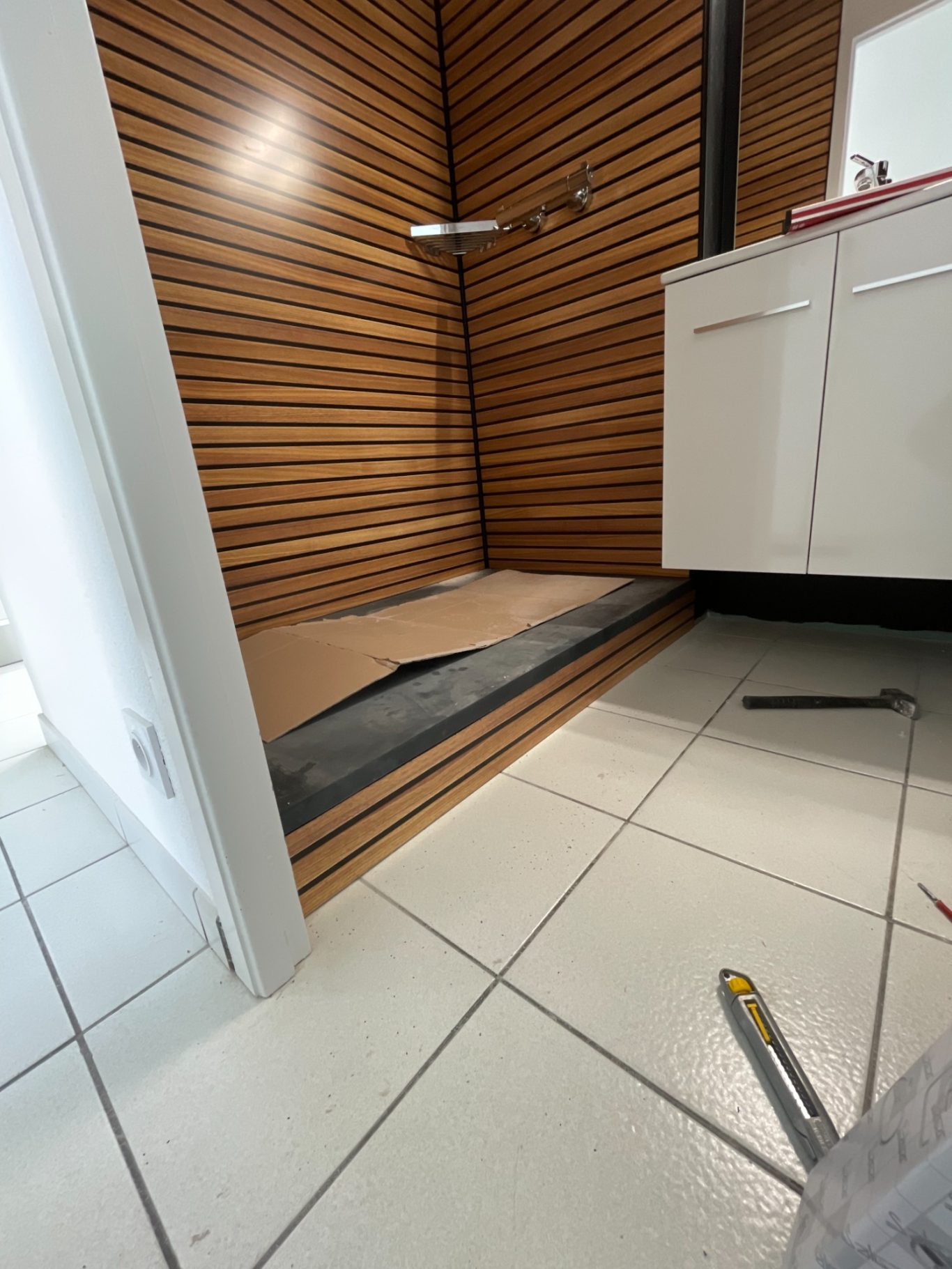 Douche à l'italienne en cours d'aménagement avec carrelage et murs en bois.