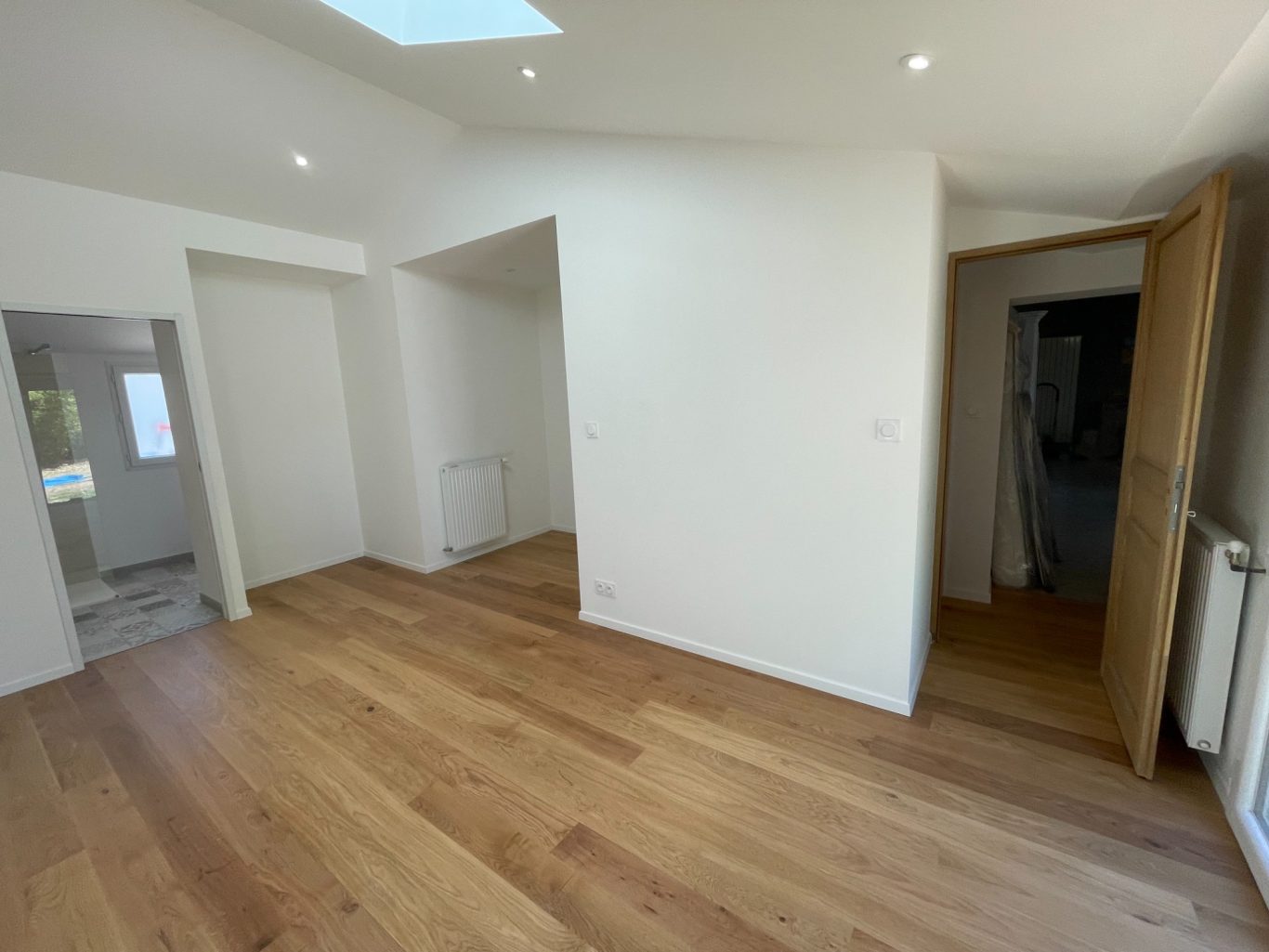 Intérieur lumineux d'une pièce moderne avec un sol en bois et des murs blancs.