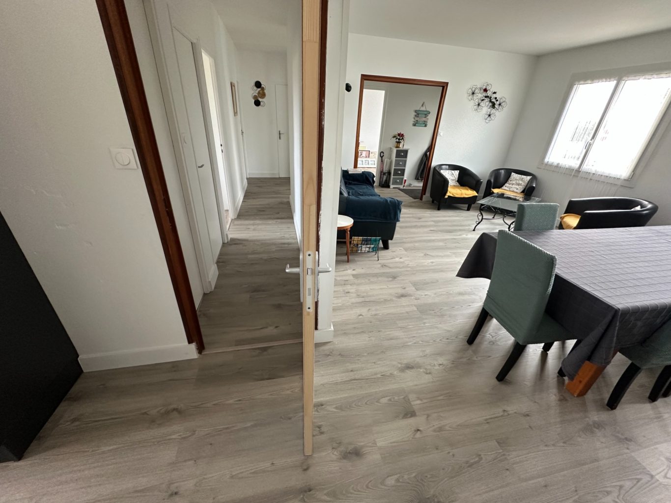 Intérieur moderne et lumineux avec un couloir et un salon meublé.