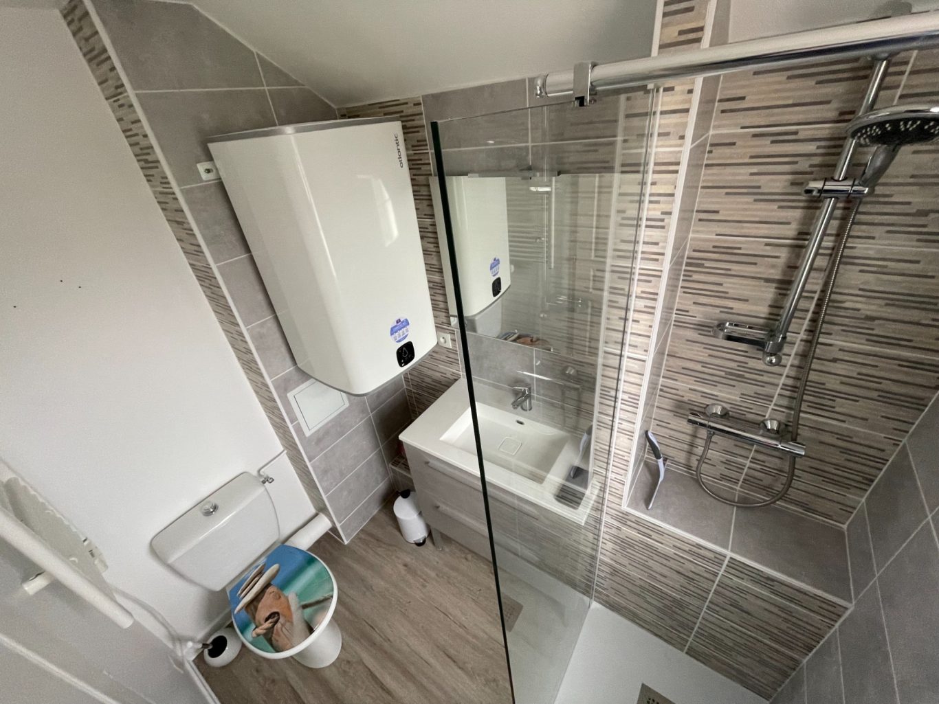Salle de bain moderne avec douche, lavabo et toilettes. Revêtement en carrelage.