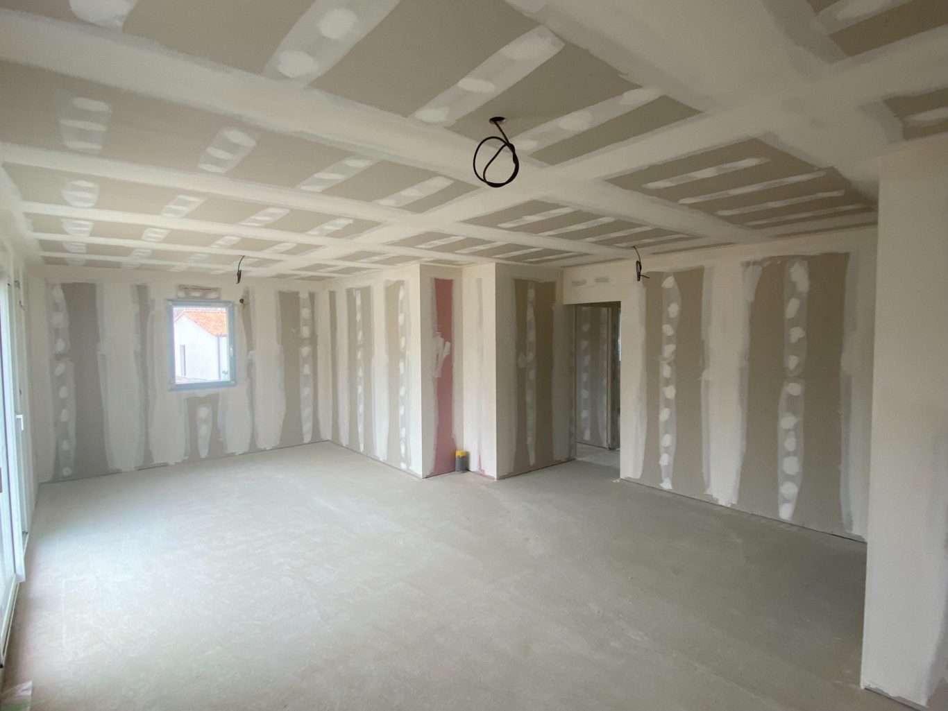 Intérieur d'une pièce en cours de construction avec murs non finis et plancher nu.