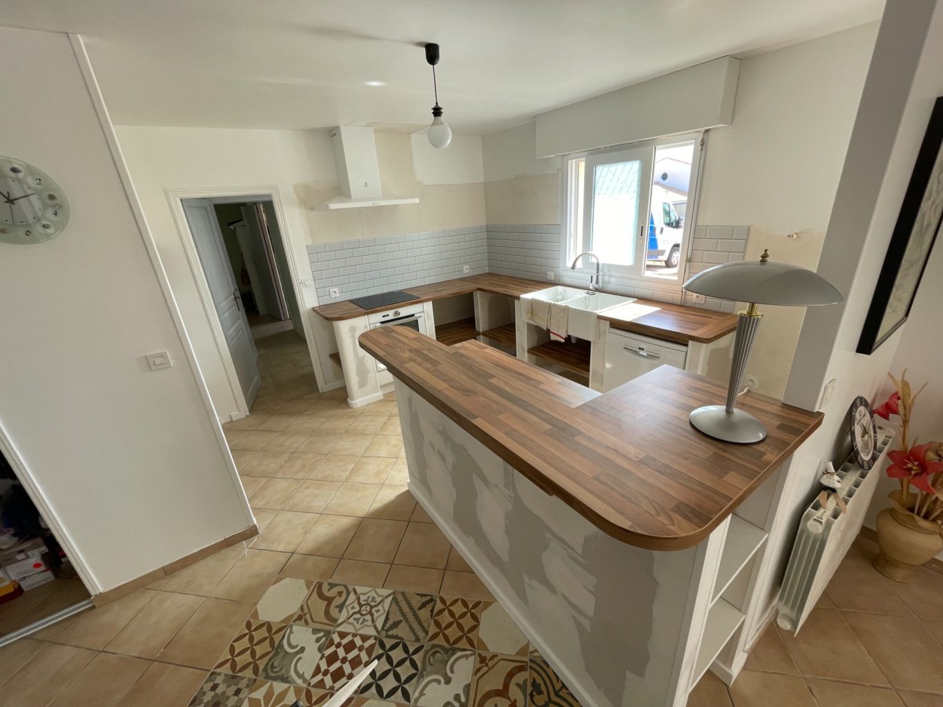 Cuisine moderne avec un bar en bois, murs clairs et carrelage beige.