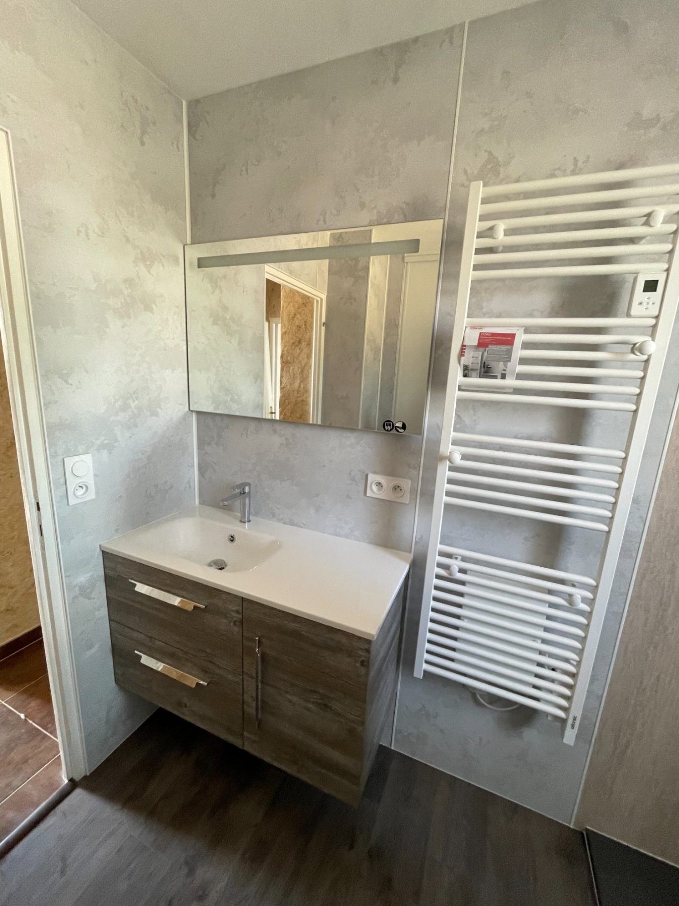 Salle de bain moderne avec meuble lavabo, miroir et radiateur contemprain.