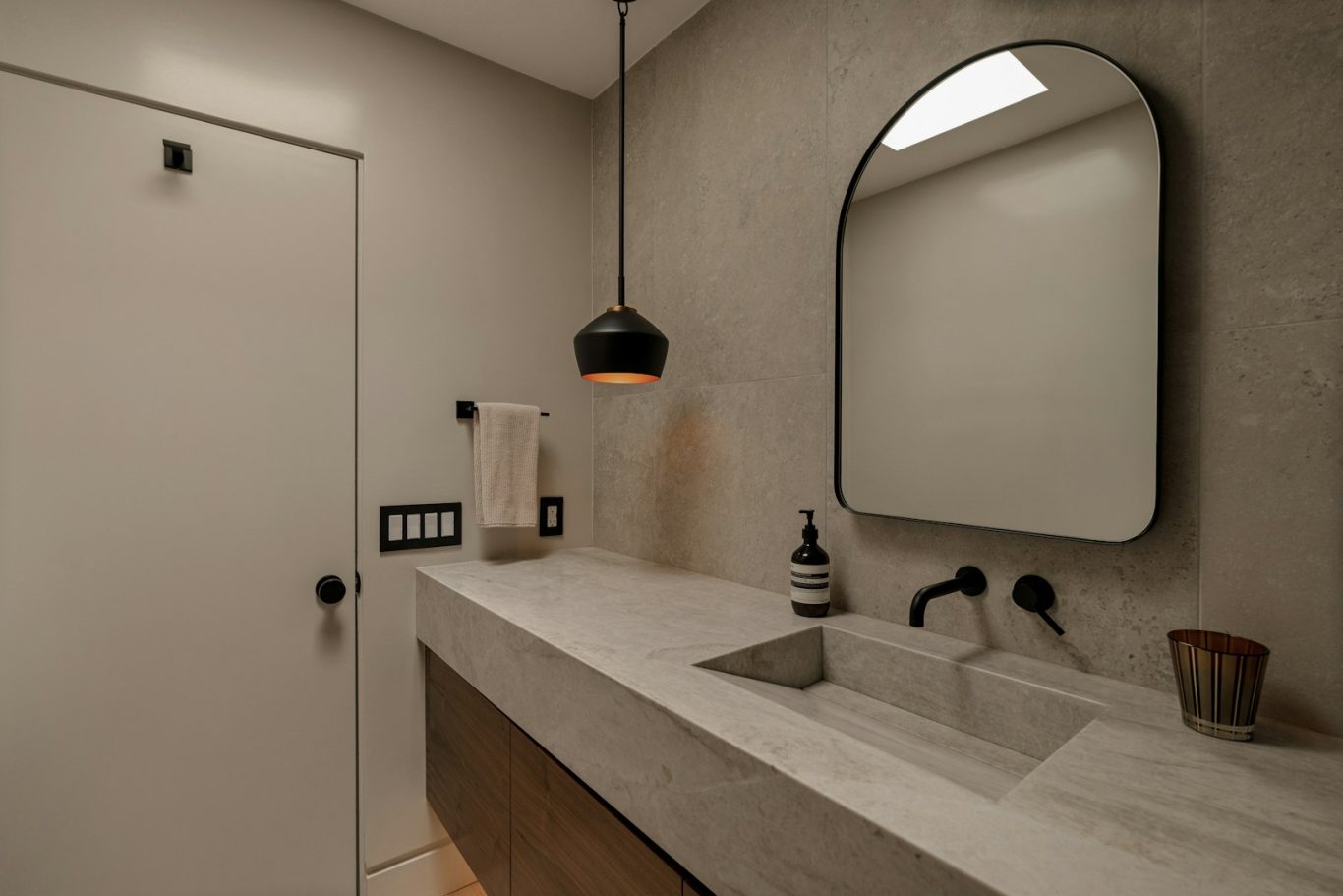 Salle de bain moderne avec miroir, lavabo et décoration minimaliste.