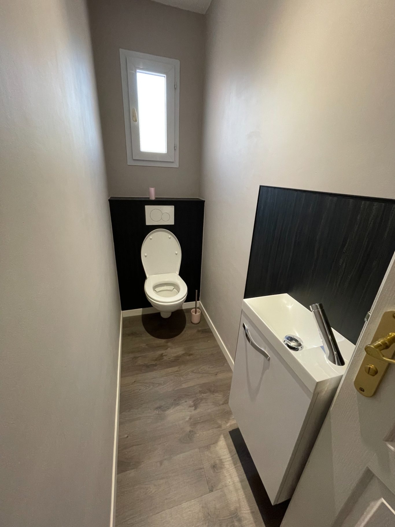 Toilet dans un espace étroit avec un lavabo et une fenêtre.