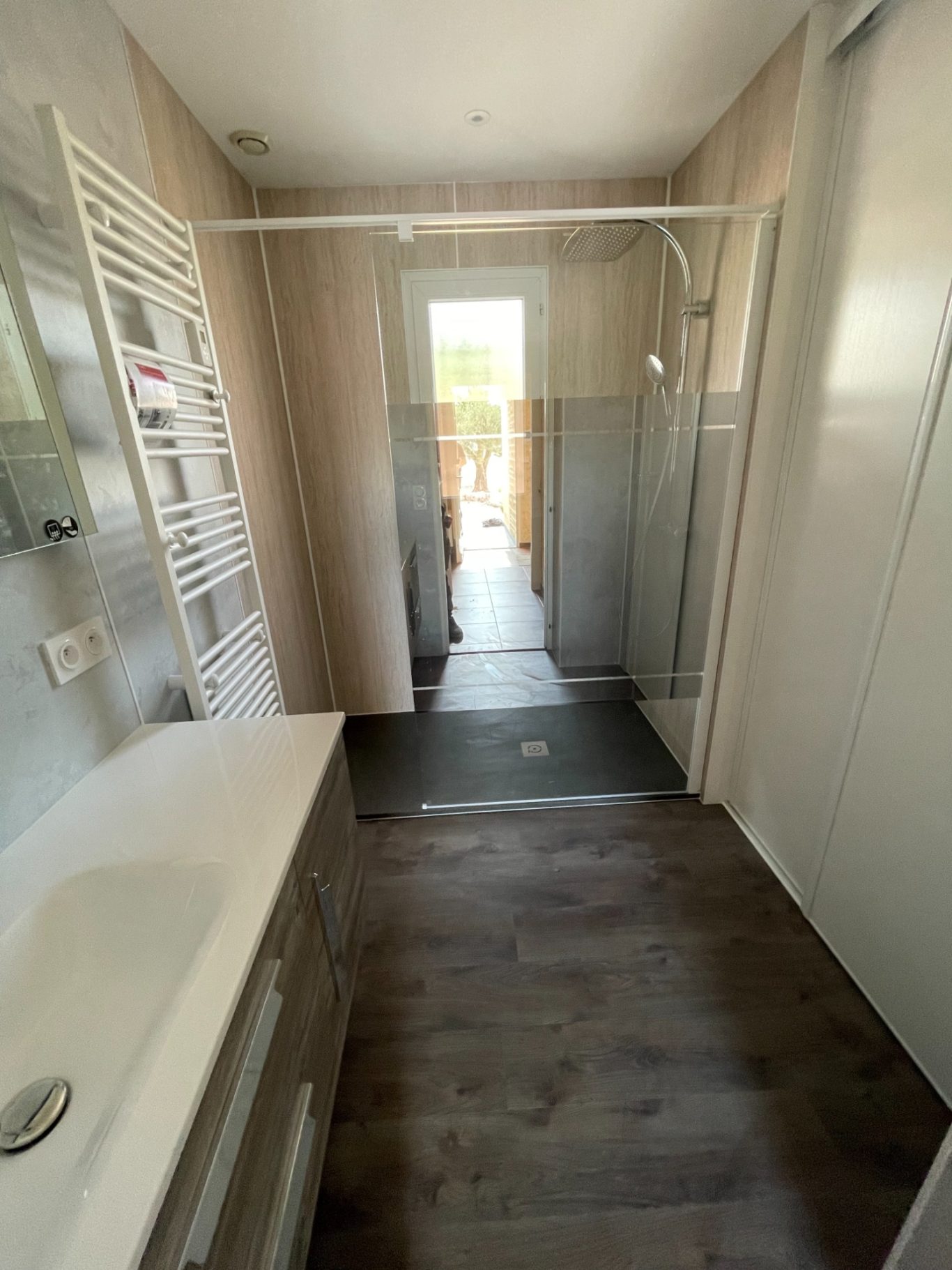 Salle de bain moderne avec douche vitrée et meuble sous lavabo. Sol en bois.