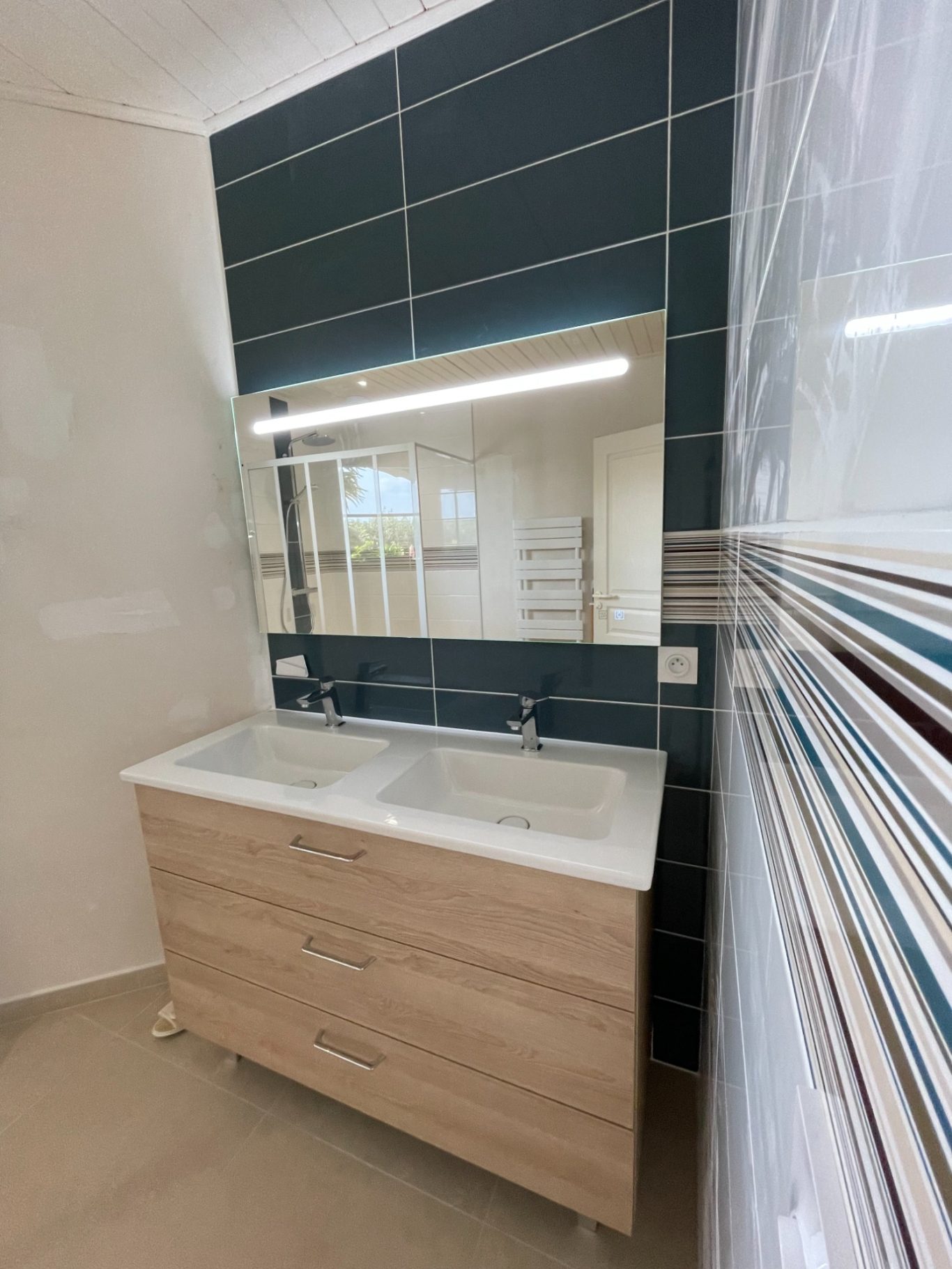Meuble de salle de bain moderne avec miroir et carrelage coloré.